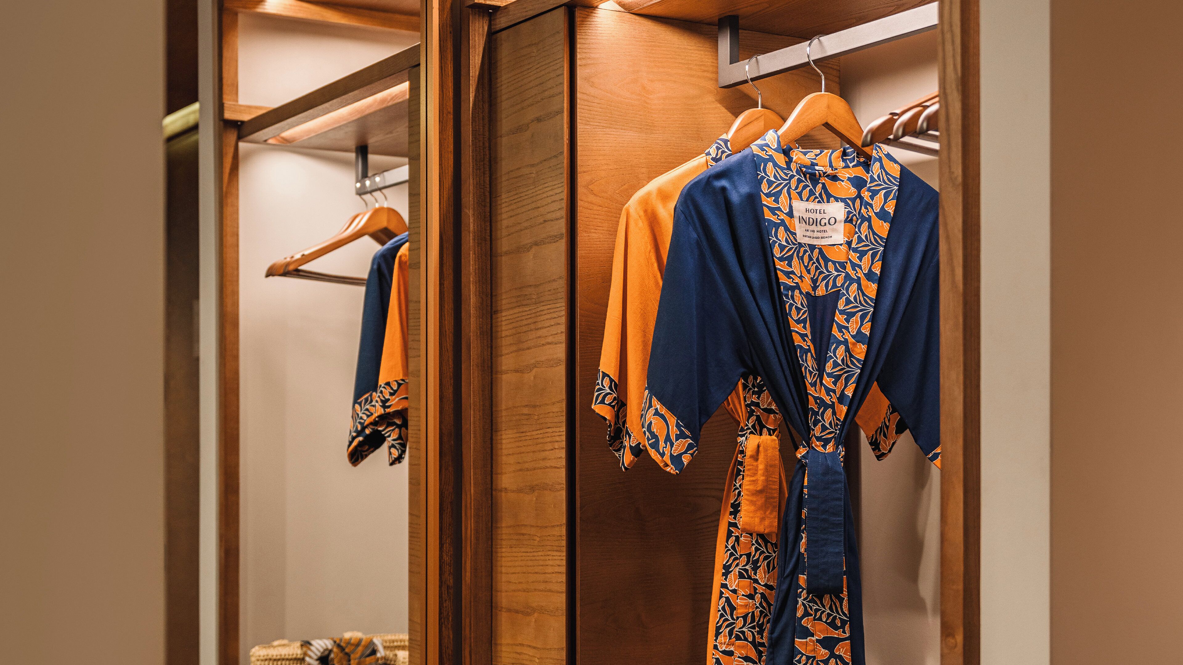 A hotel closet with wooden doors and a hanging rack.