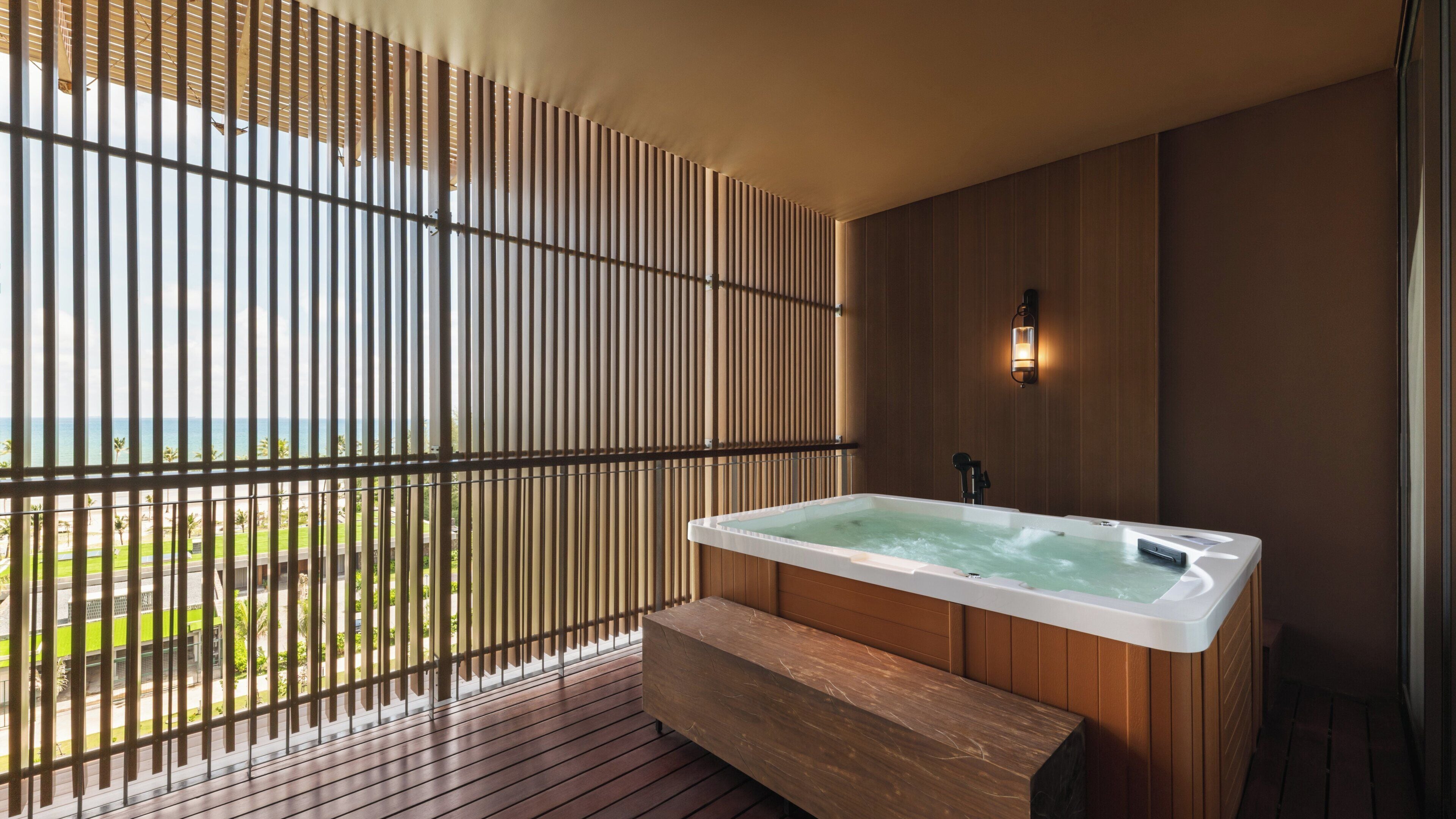 Ein Wellnessbereich mit Whirlpool, Holzböden und Meerblick.