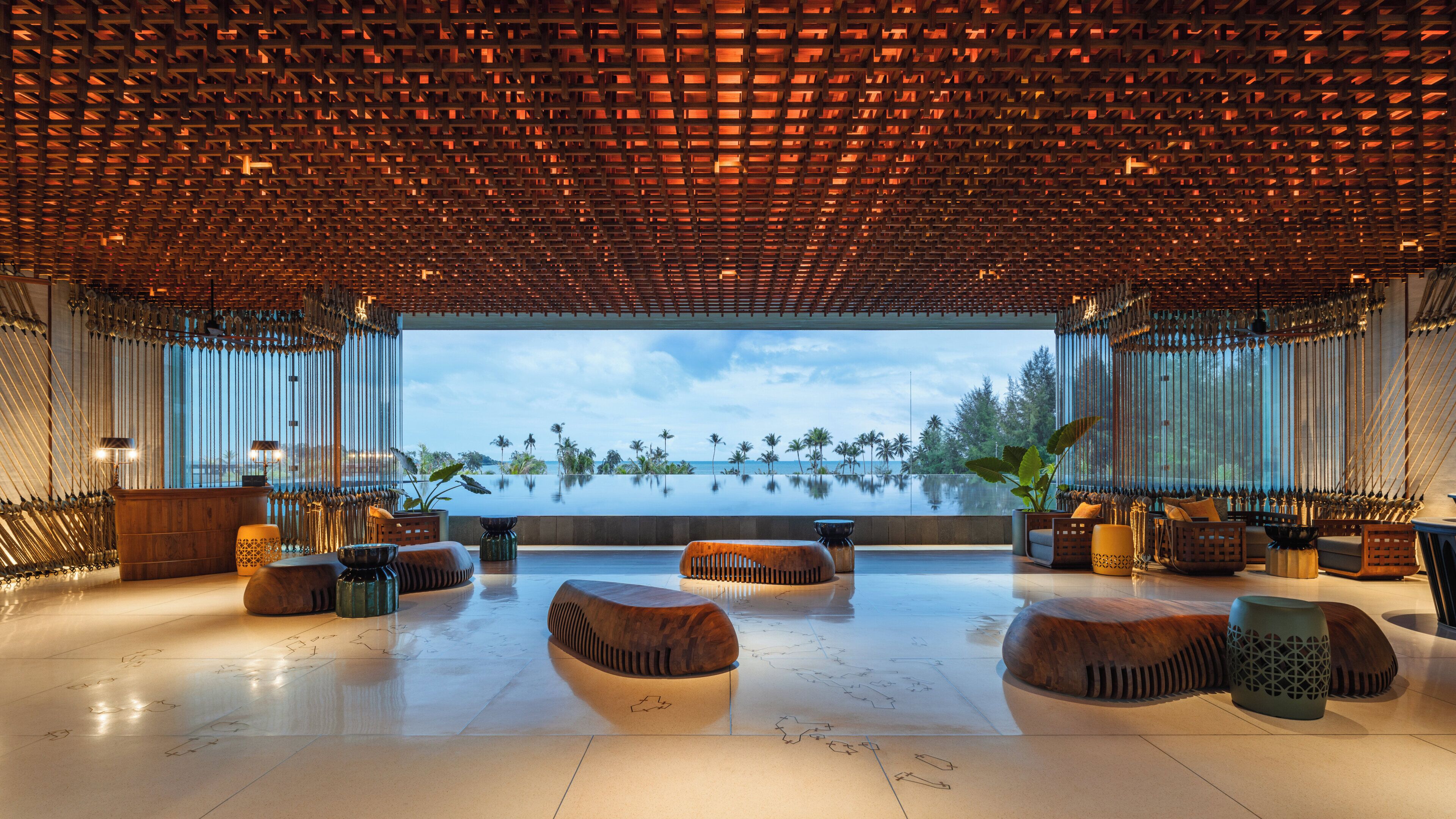 A spacious, modern lounge area with a view of a calm body of water and palm trees.