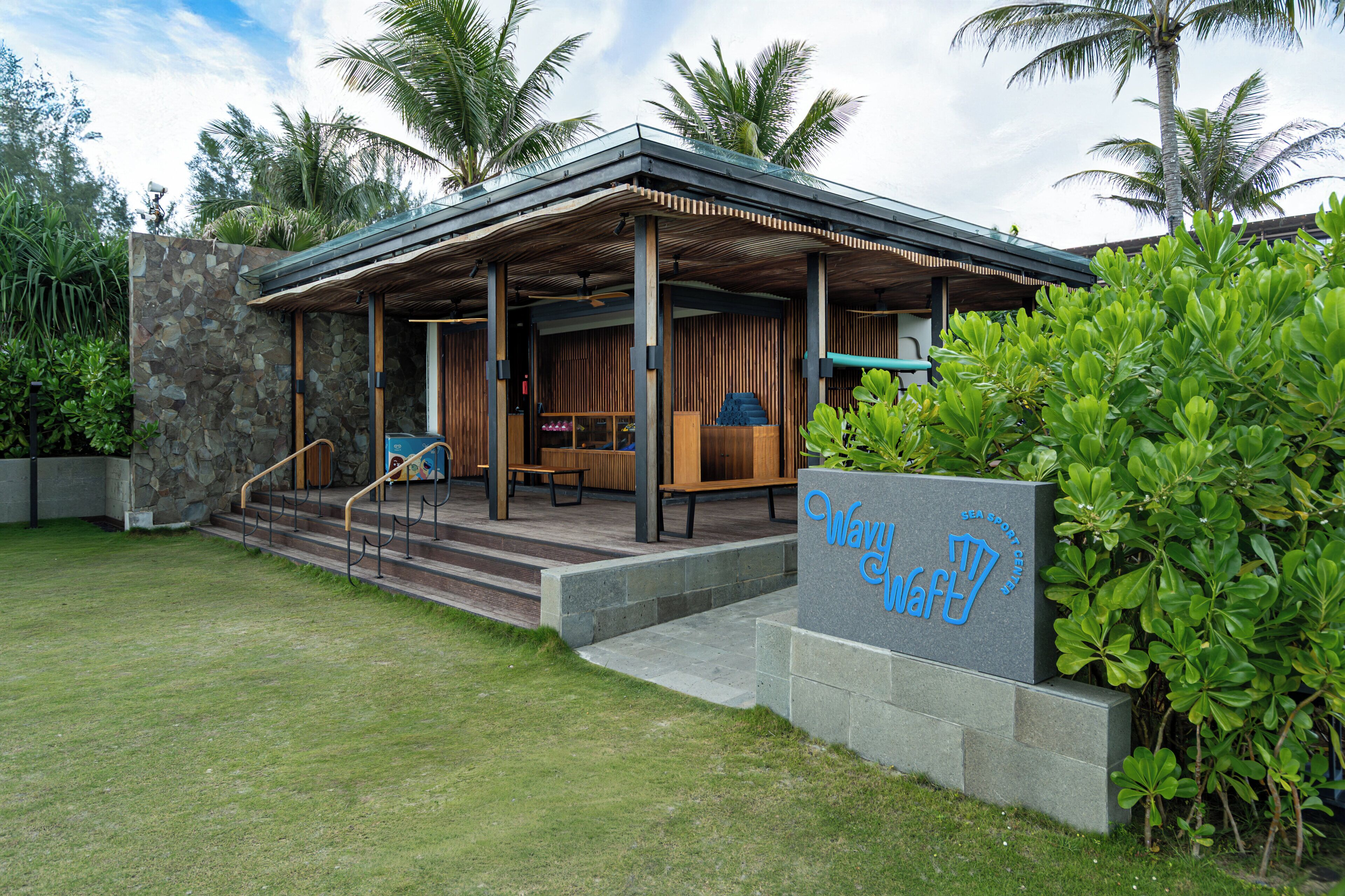 A modern building with a covered entrance, outdoor seating, and a sign reading 'Wavy Waft'.