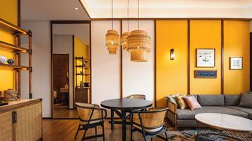 A modern living room with a sofa, a round table, wicker chairs, and a coffee machine.