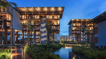 A modern hotel with multiple floors, outdoor seating, and a water feature.