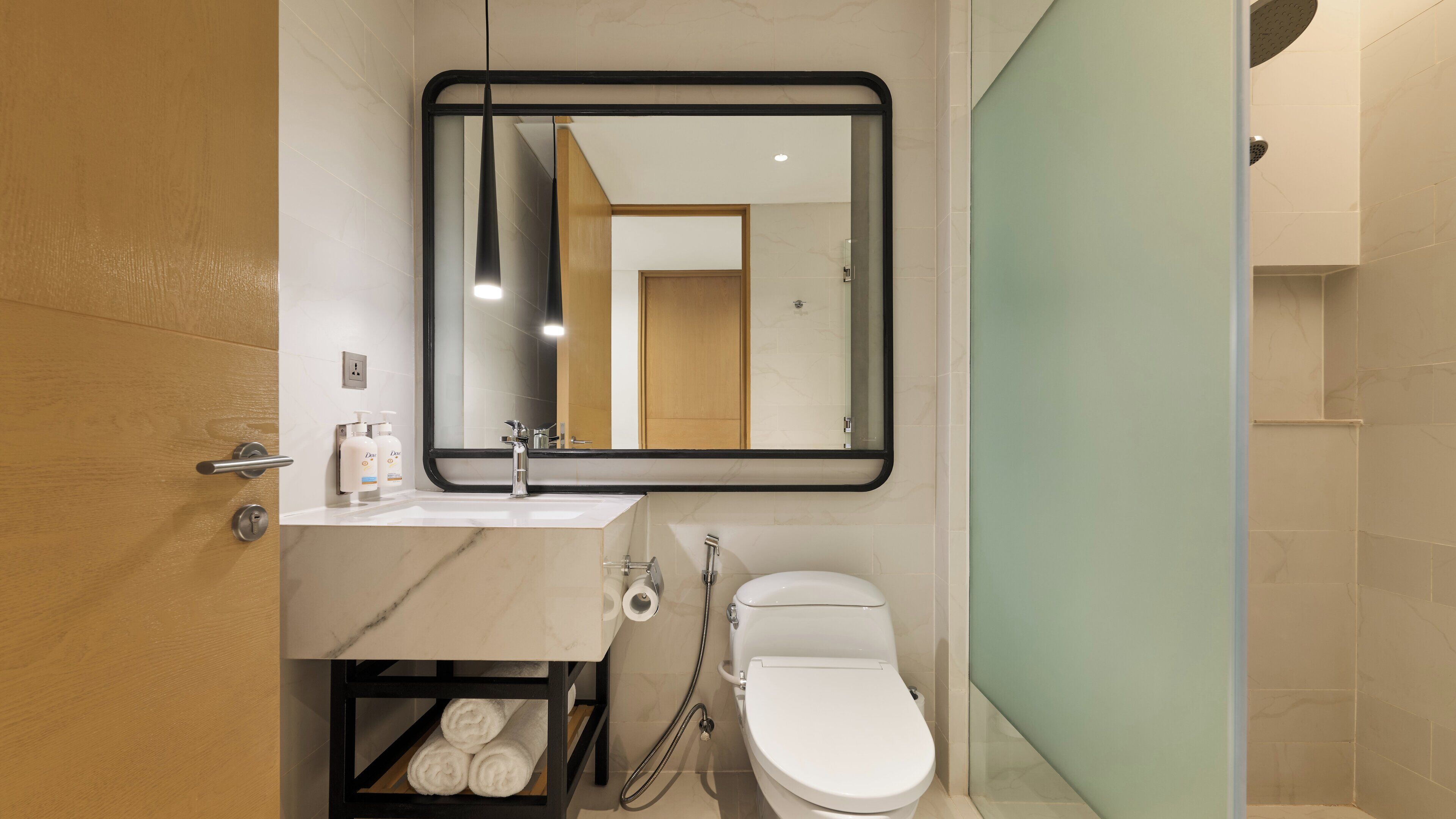 A modern bathroom with a marble sink, a toilet, and a shower area.