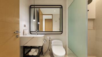 A modern bathroom with a marble sink, a toilet, and a shower area.