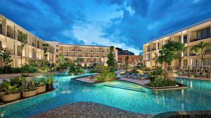 Et hotel med en central swimmingpool omgivet af frodig vegetation og flere altaner.