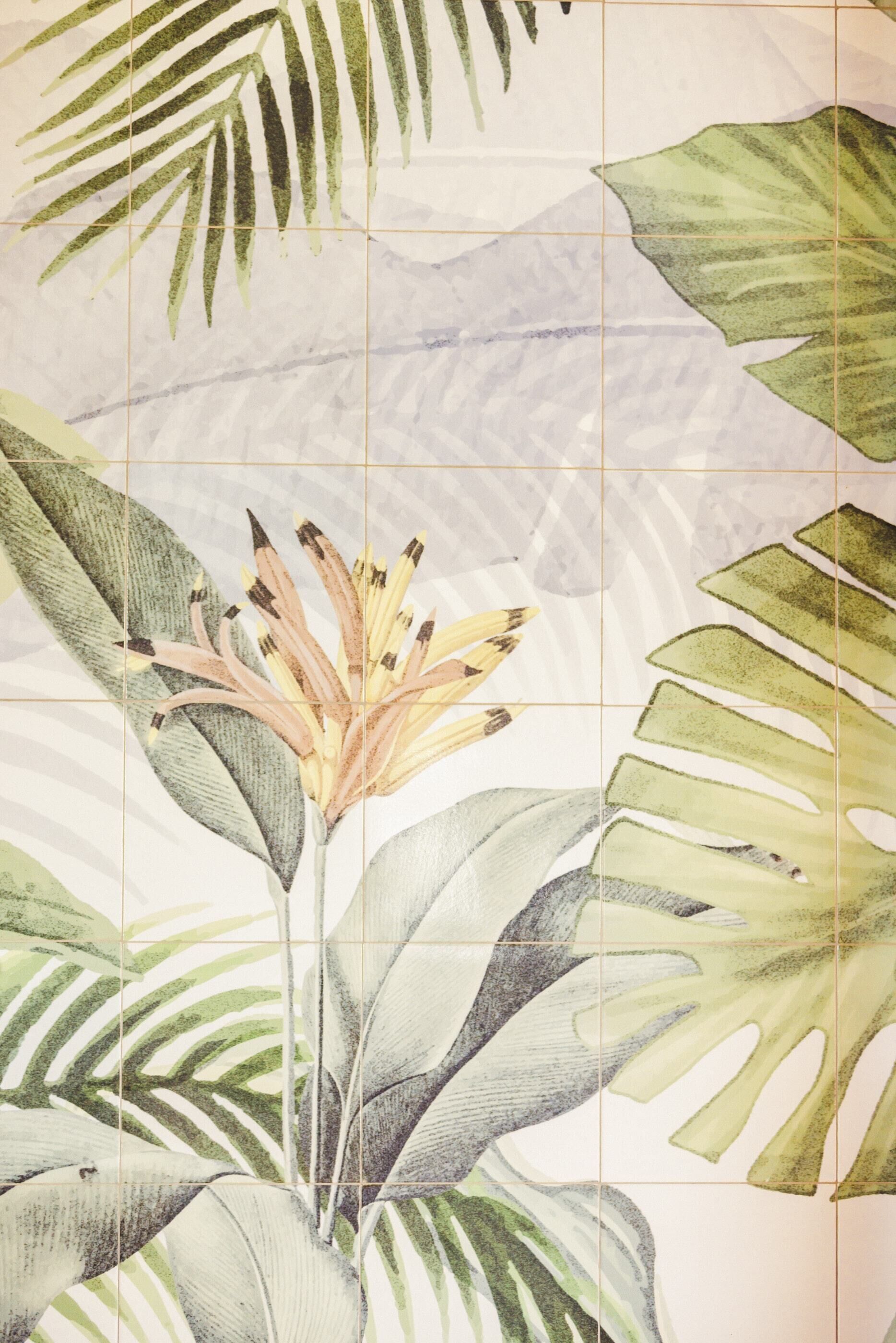 Pared de azulejos con diseño de planta tropical.