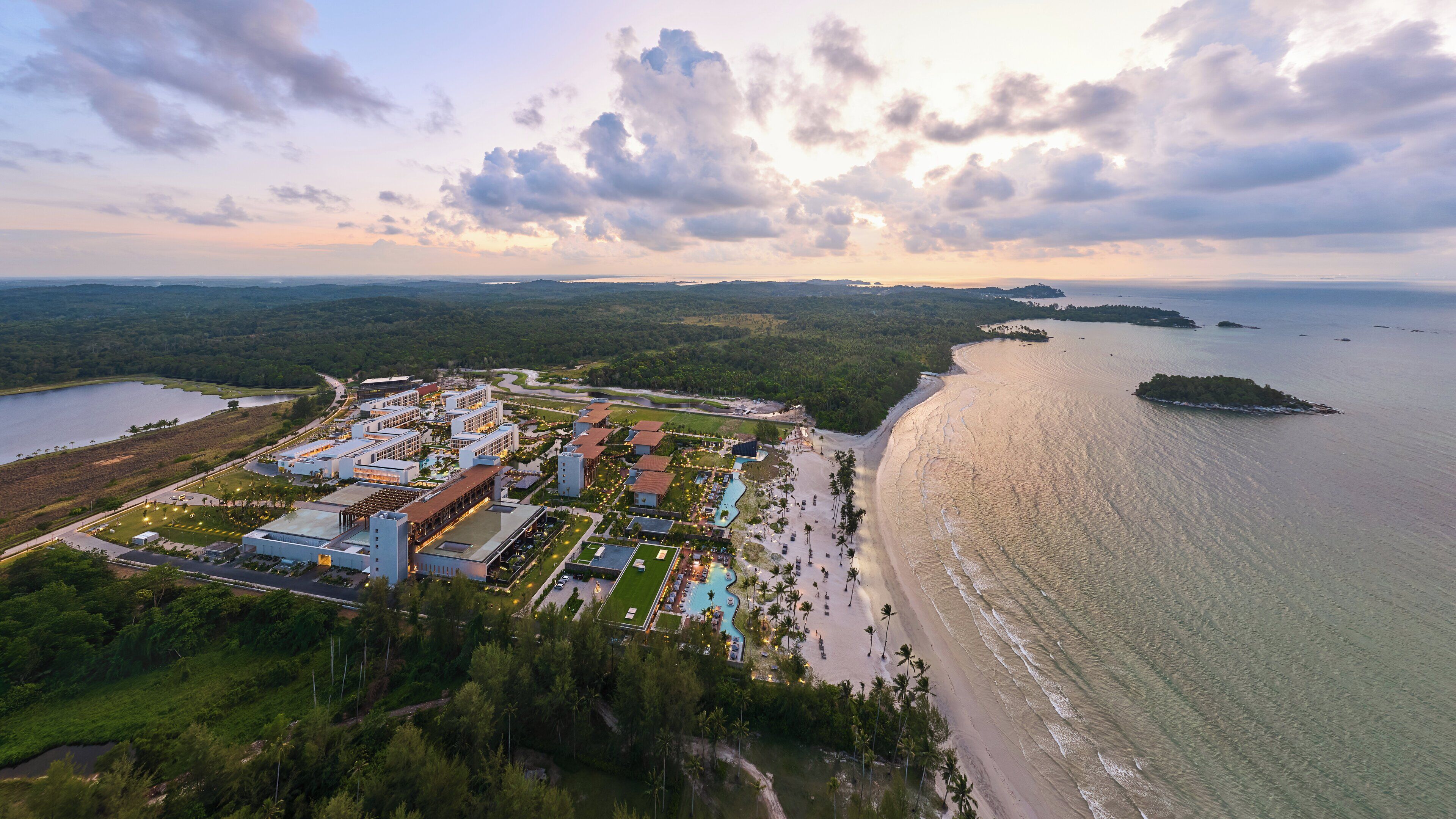Vista aérea de um resort com vários edifícios, uma praia e uma área de água.