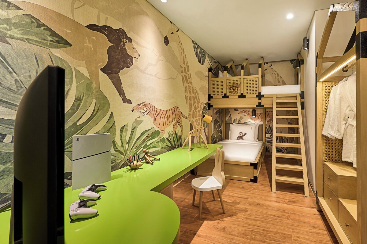 A room with a green desk, a bunk bed, a mural with animal prints, and a wooden lattice partition.