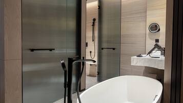 A modern bathroom with a freestanding bathtub, a glass shower enclosure, and a marble countertop with a sink and mirror.