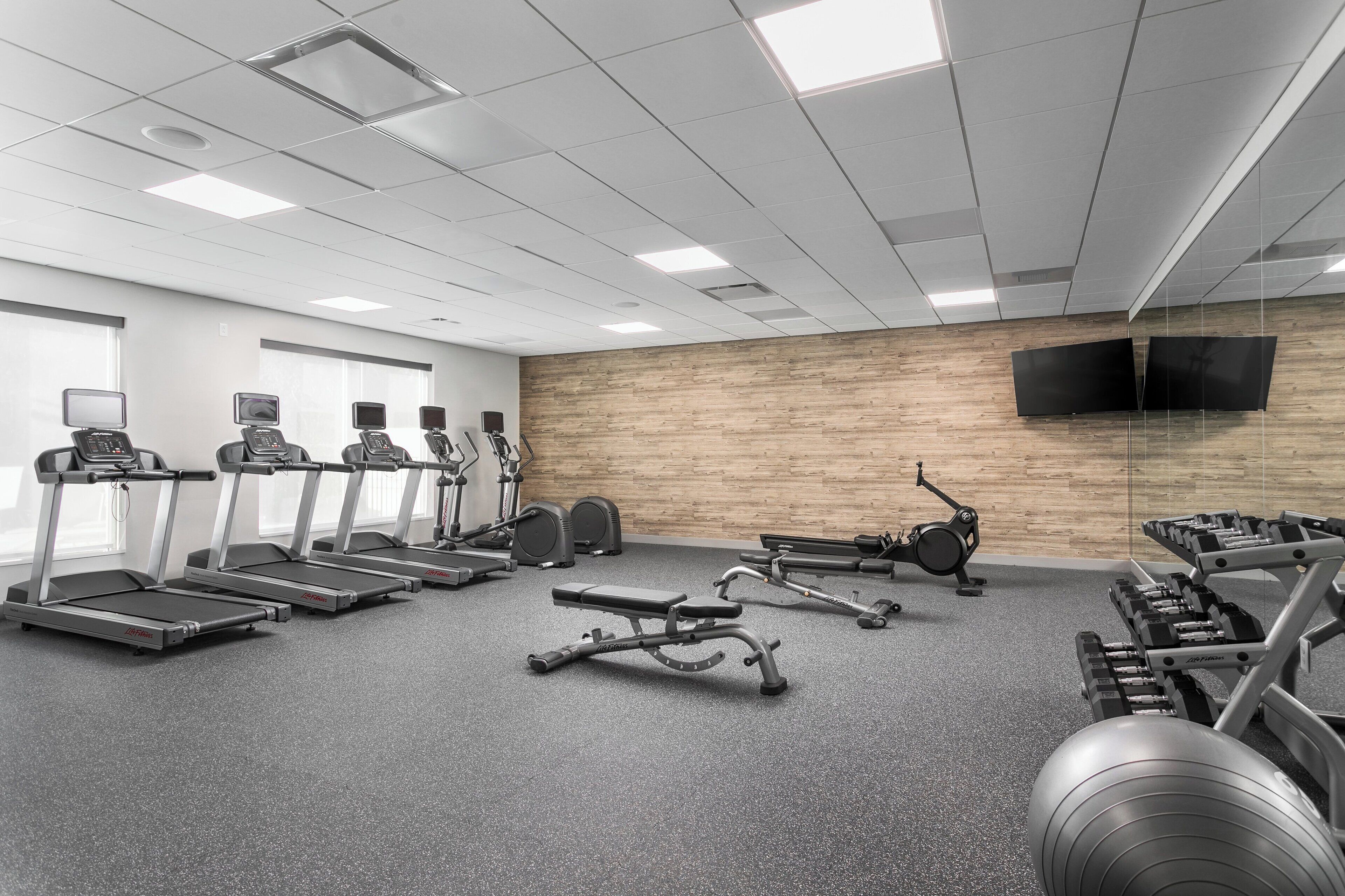 A gym with treadmills, elliptical machines, and weightlifting equipment.