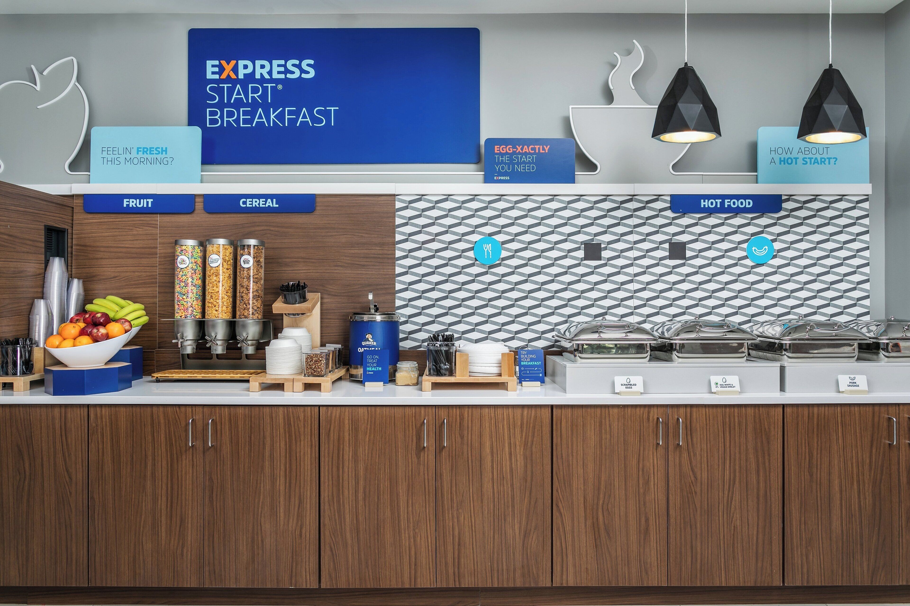 A breakfast buffet area with labeled sections for fruit, cereal, and hot food.