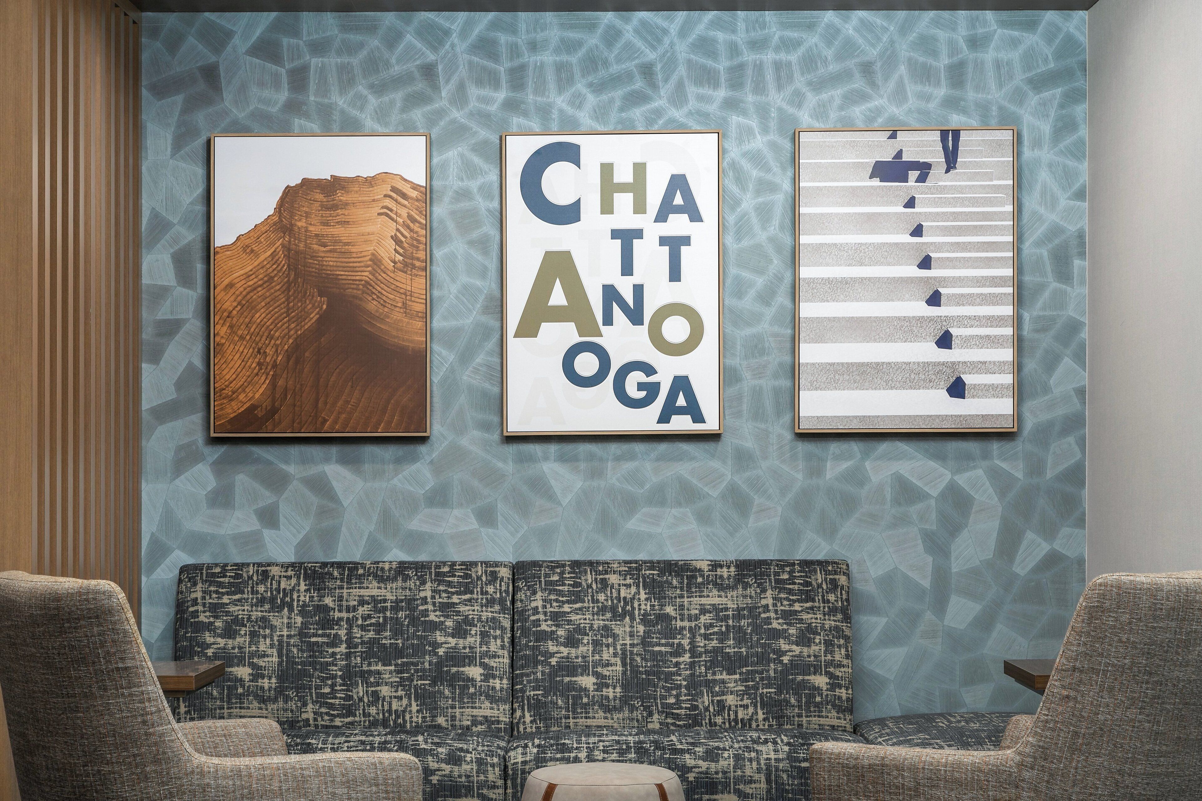Una habitación con un papel tapiz estampado, un sofá y dos sillones. Se observan tres cuadros enmarcados en la pared.