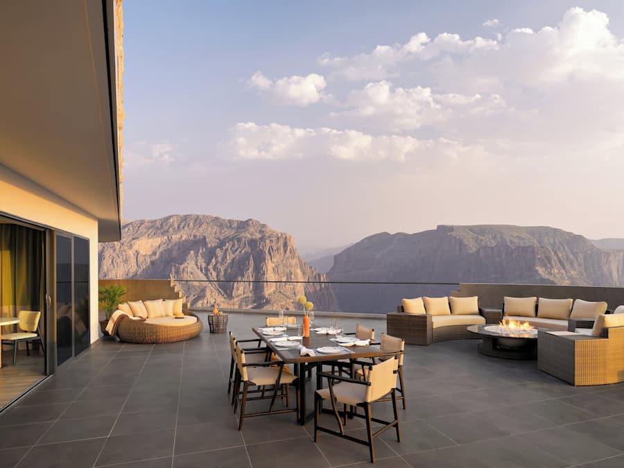 Una terraza en la azotea con zona de comedor, asientos y vistas a montañas.