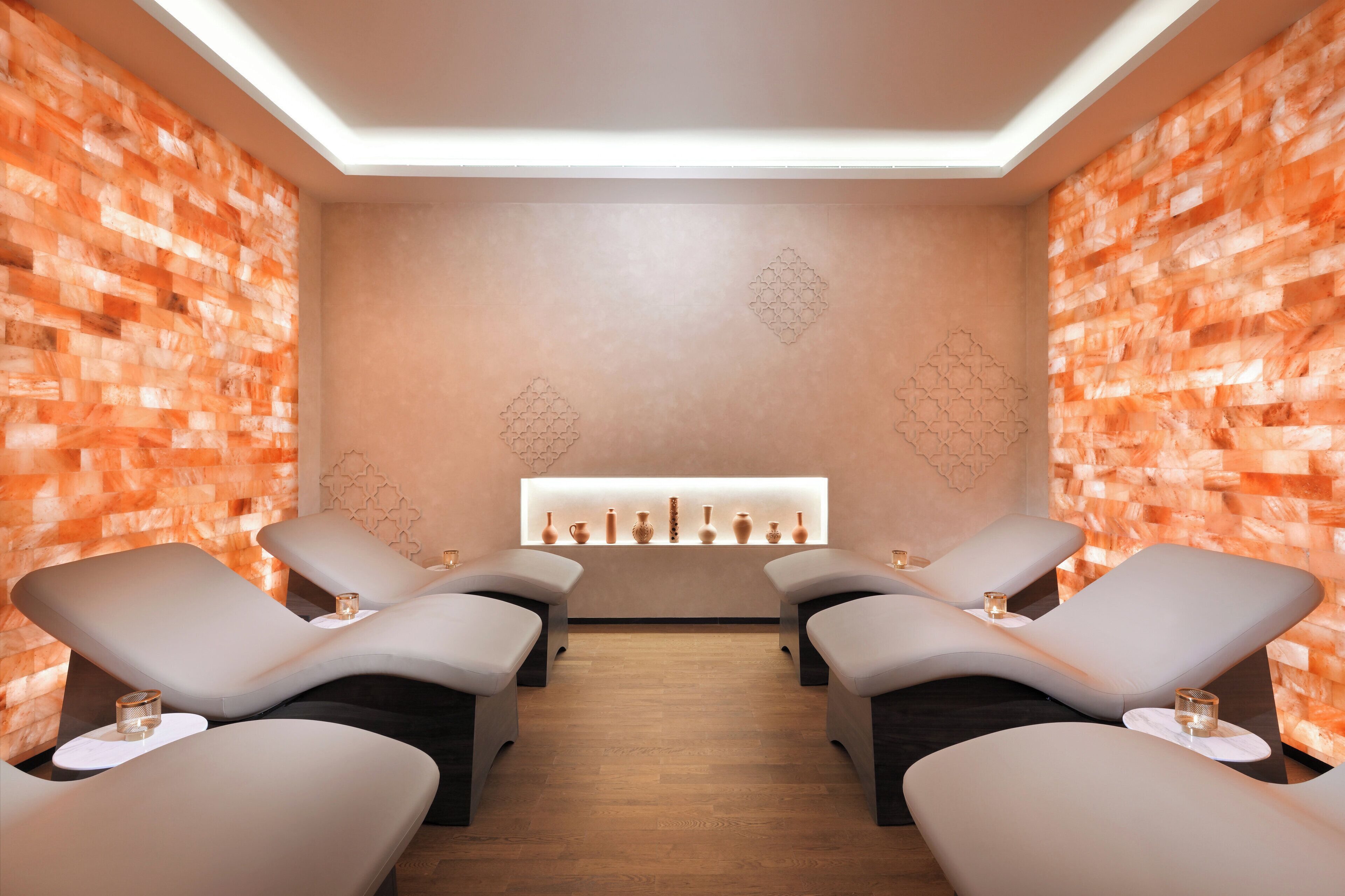 Une salle de spa équipée de deux fauteuils inclinables, d’une étagère murale agrémentée d’objets décoratifs et d’un mur orné de motifs.