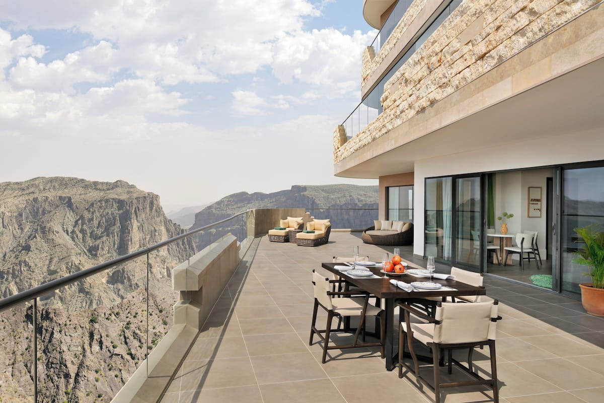 Une terrasse aménagée avec un coin repas offrant une vue sur un paysage montagneux.