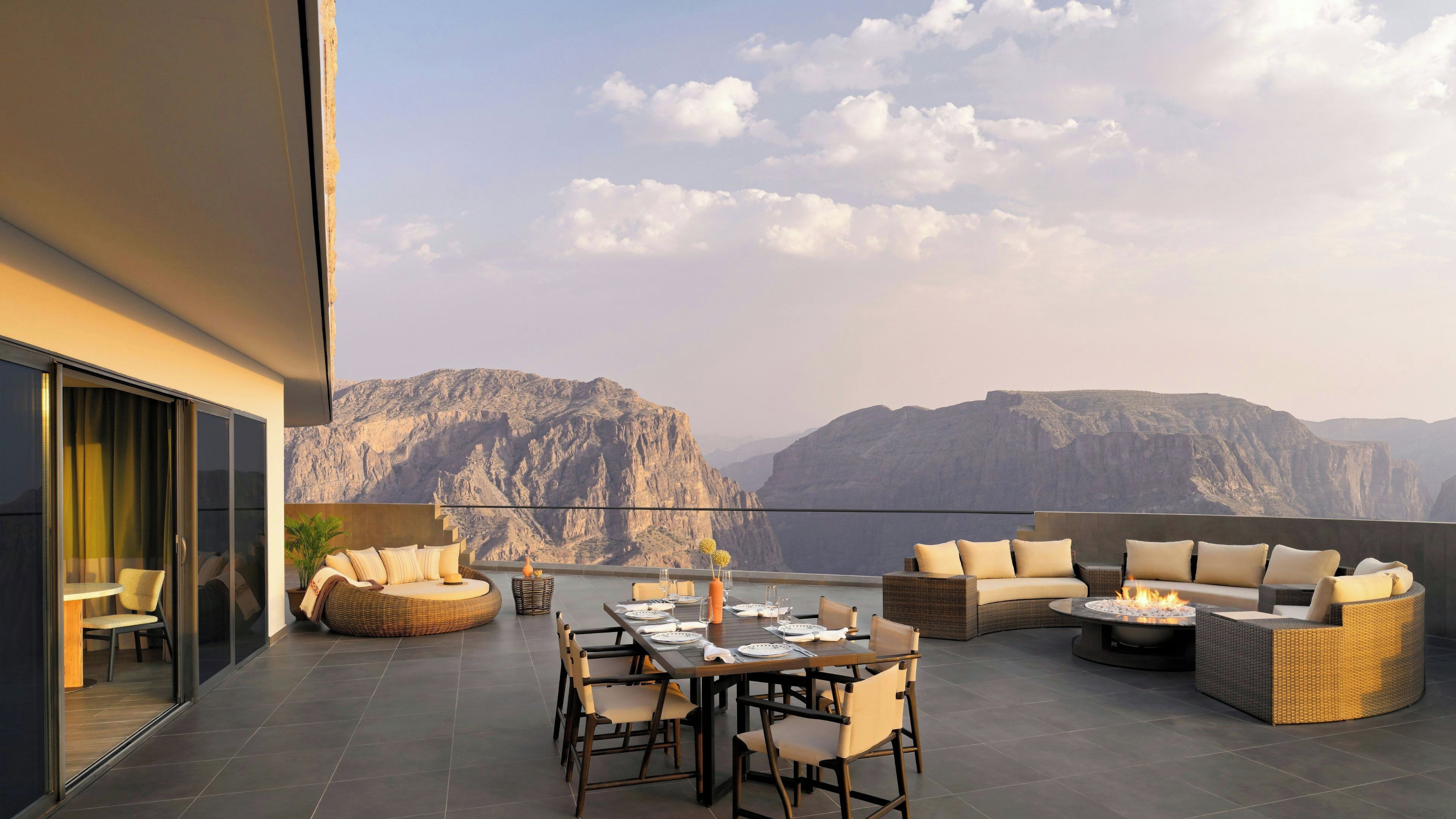 Une terrasse dotée d’une table à manger, de chaises et de canapés, offrant une vue sur un paysage montagneux.