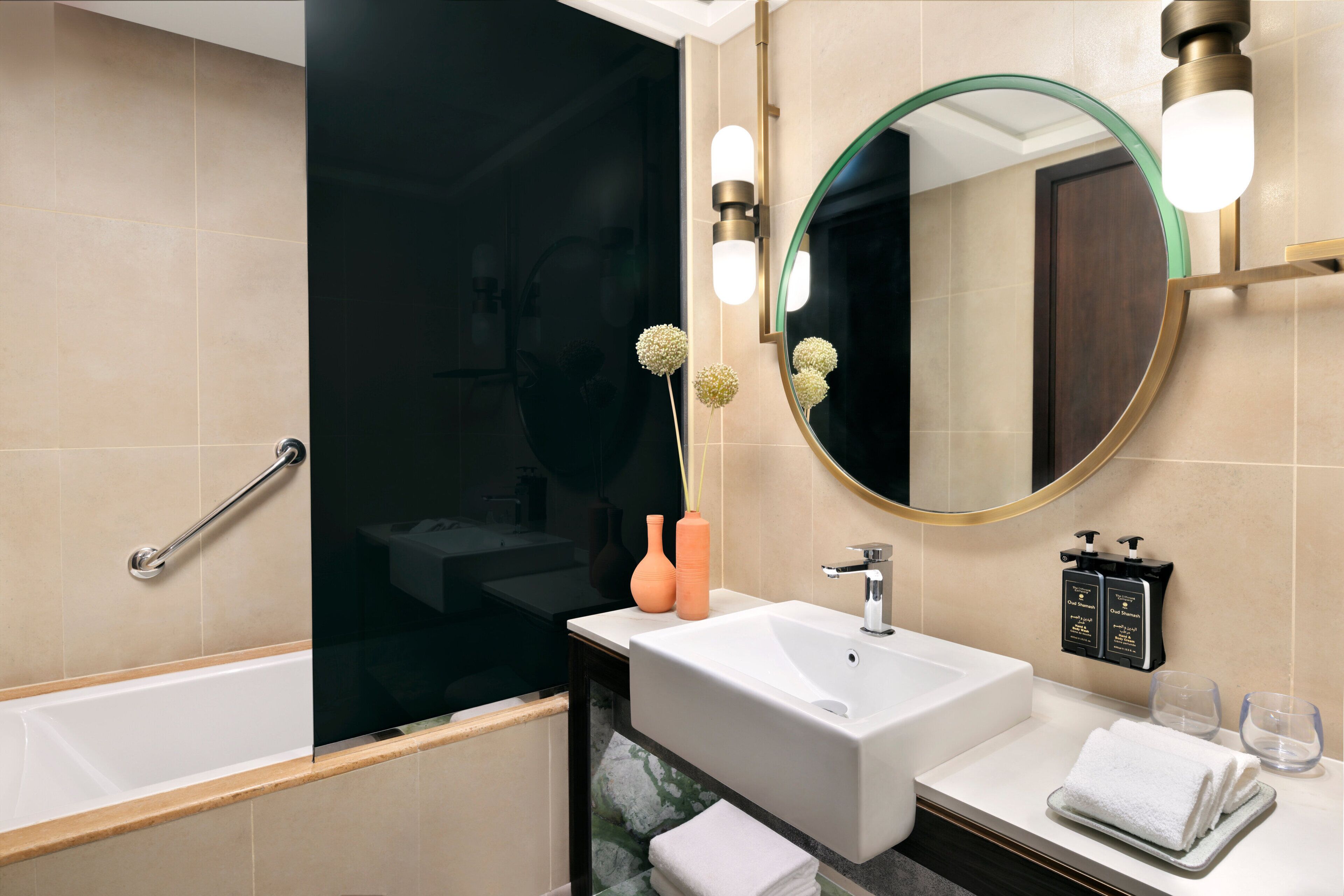 A modern bathroom with a bathtub, sink, mirror, and towel rack.