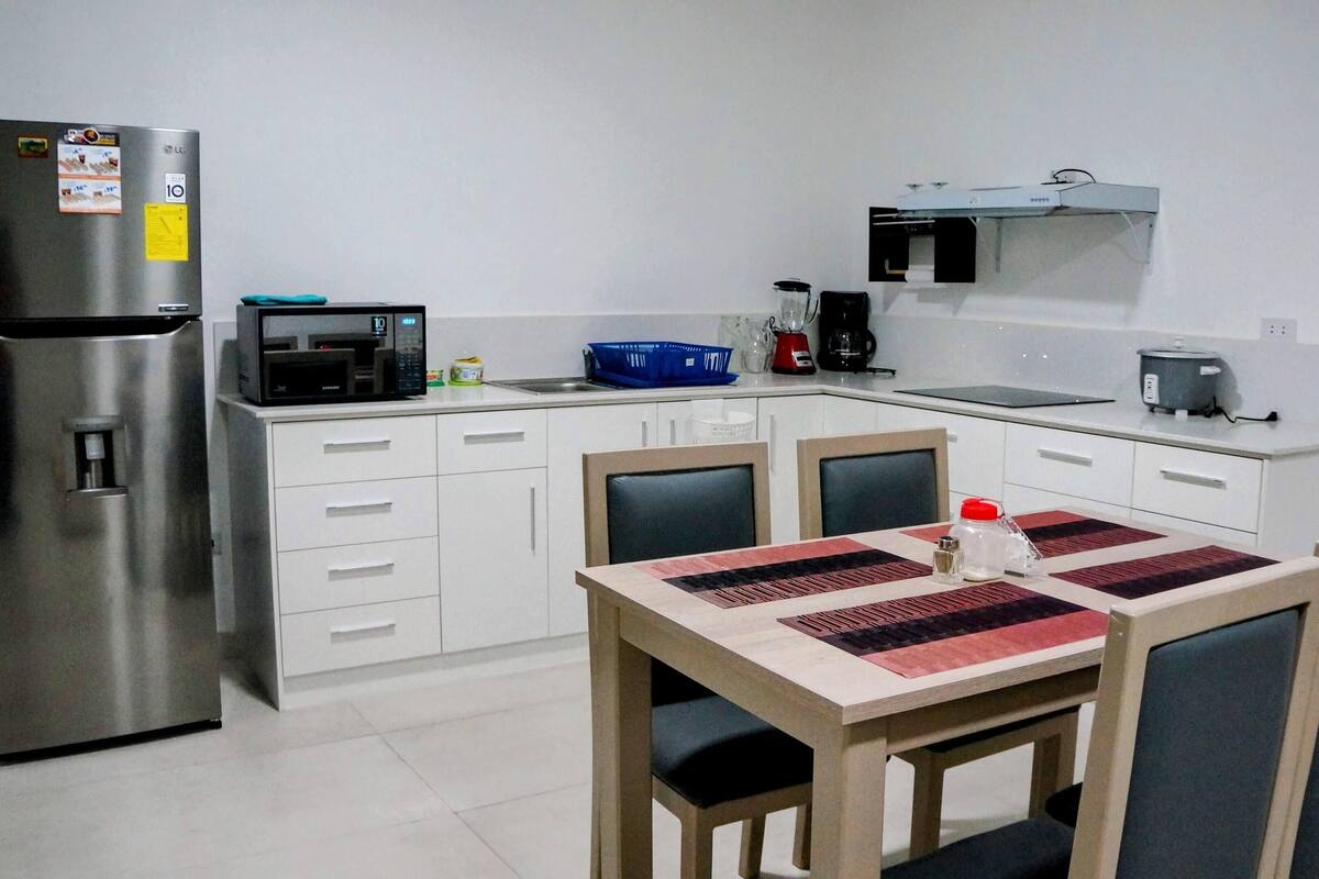 A compact kitchen with a refrigerator, microwave, and a small dining area with a table and chairs.