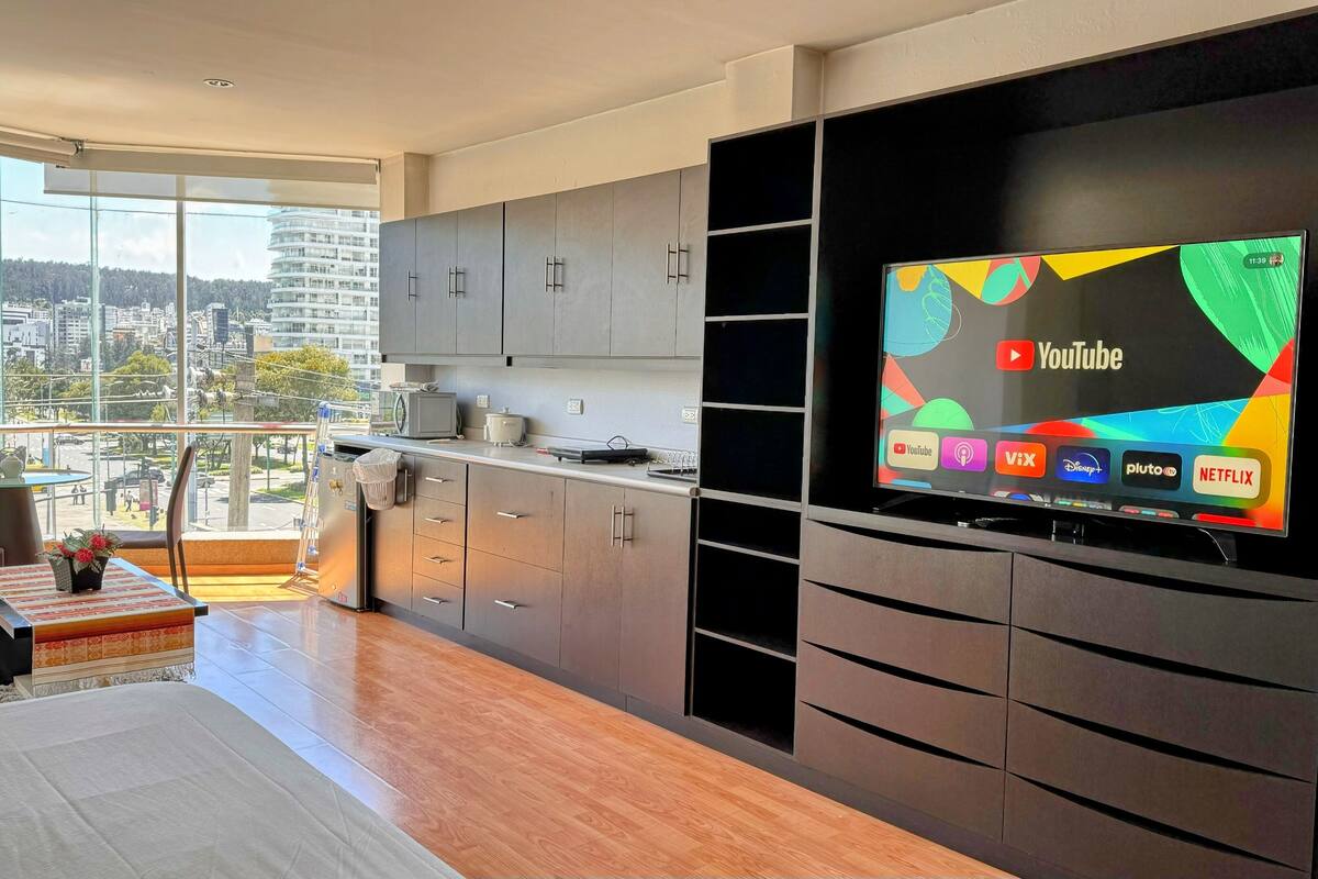 A modern kitchen with a large flat-screen TV displaying various streaming services.