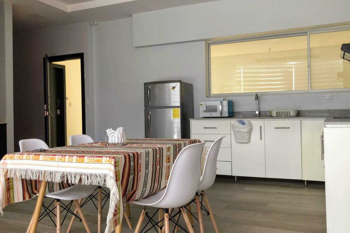 A modern kitchen with white cabinets, a stainless steel refrigerator, and a microwave.