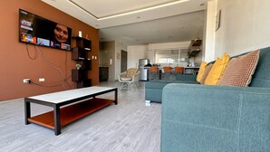 A modern living room with a grey sofa, a coffee table, and a TV mounted on the wall. - Edificio Tofino (Quito)