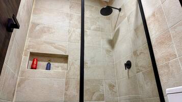 A shower area with beige tiles and a black showerhead.