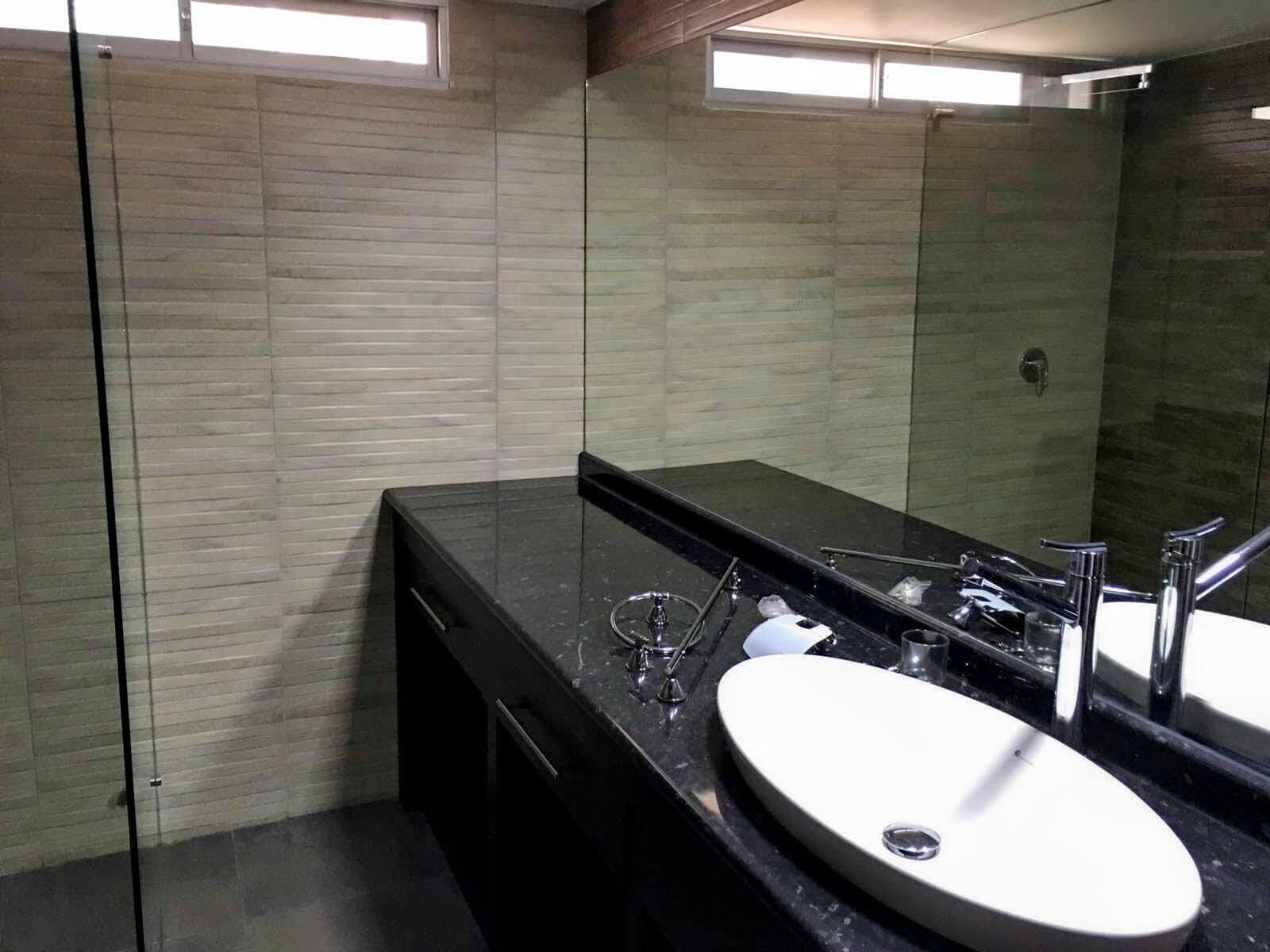 A modern bathroom with a black countertop, a white sink, and a large mirror.