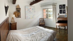 Ein Schlafzimmer mit einem Bett, einem Schreibtisch, einem Stuhl, einer Wanduhr und einer Karte.