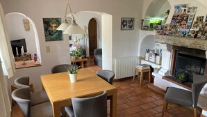 Ein gemütliches Wohnzimmer mit Kamin, ein Essbereich mit Holztisch und Stühlen sowie ein Flur mit Bogen.
