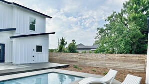 Ein modernes Haus mit Swimmingpool und zwei Liegestühlen.