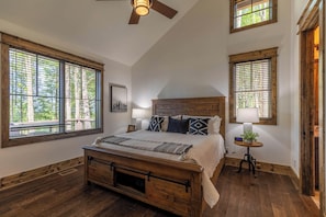 A bedroom with a large bed, wooden headboard, and two windows with blinds. - Sip Sip Hooray at Eagles Nest (Elk Park)