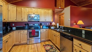 A kitchen with wooden cabinets, a microwave, a stove, and a dishwasher. - Firefly Cabin (Banner Elk)