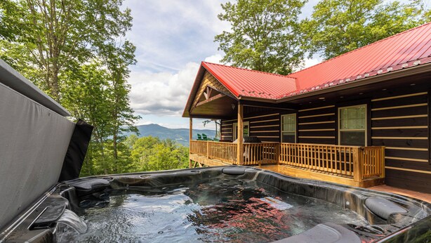 A hot tub with wooden deck and a cabin with a red roof. - Firefly Cabin (Banner Elk)