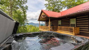 A hot tub with wooden deck and a cabin with a red roof.