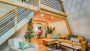 Een knus loft-achtig woongedeelte met een houten trap, een kerstboom, leren banken en een eethoek.