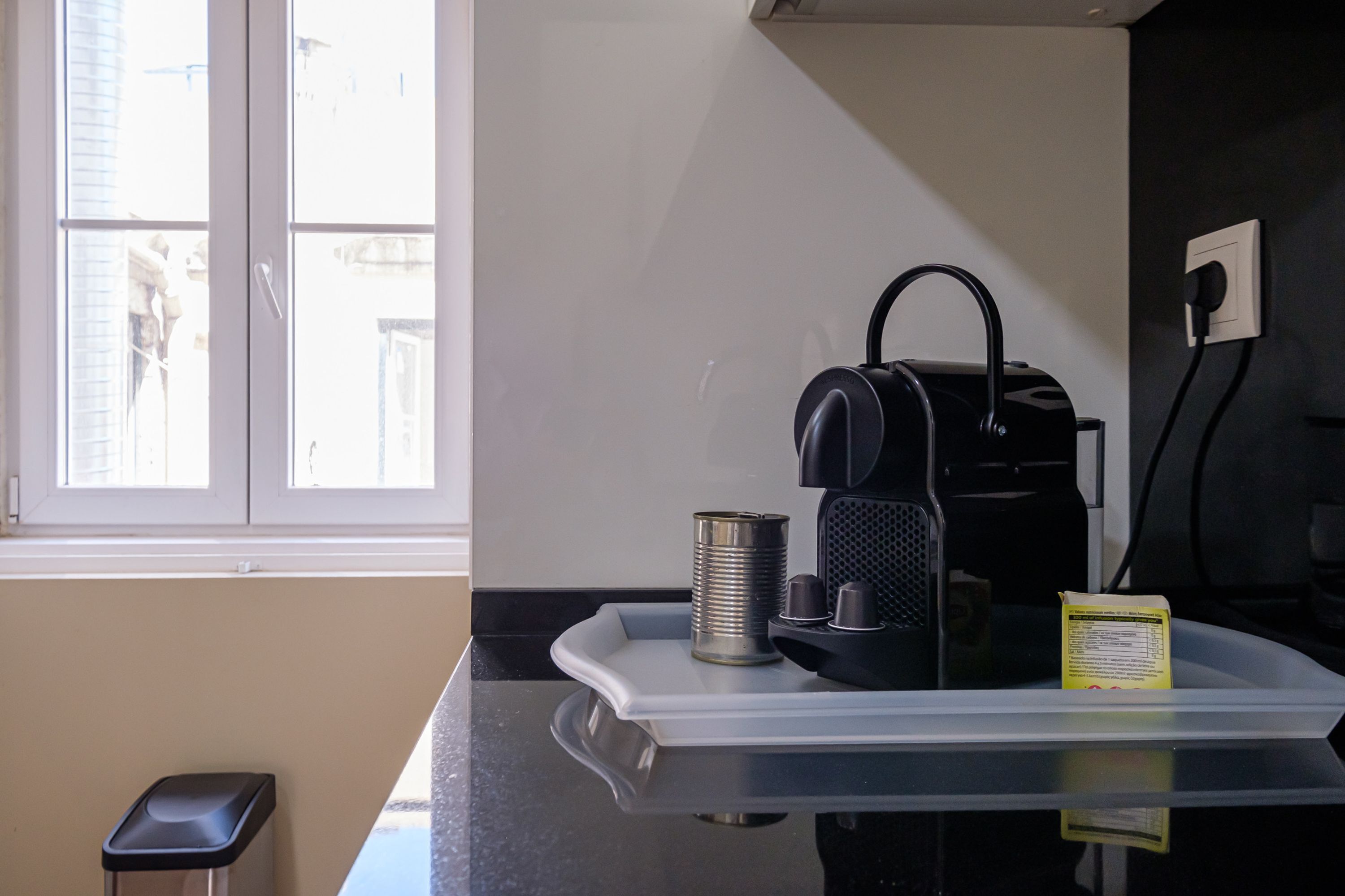 Uma bancada de cozinha com uma cafeteira, uma lata e um suporte.