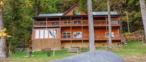 Une cabane en bois dotée de plusieurs balcons, entourée d’arbres et d’une zone herbeuse.