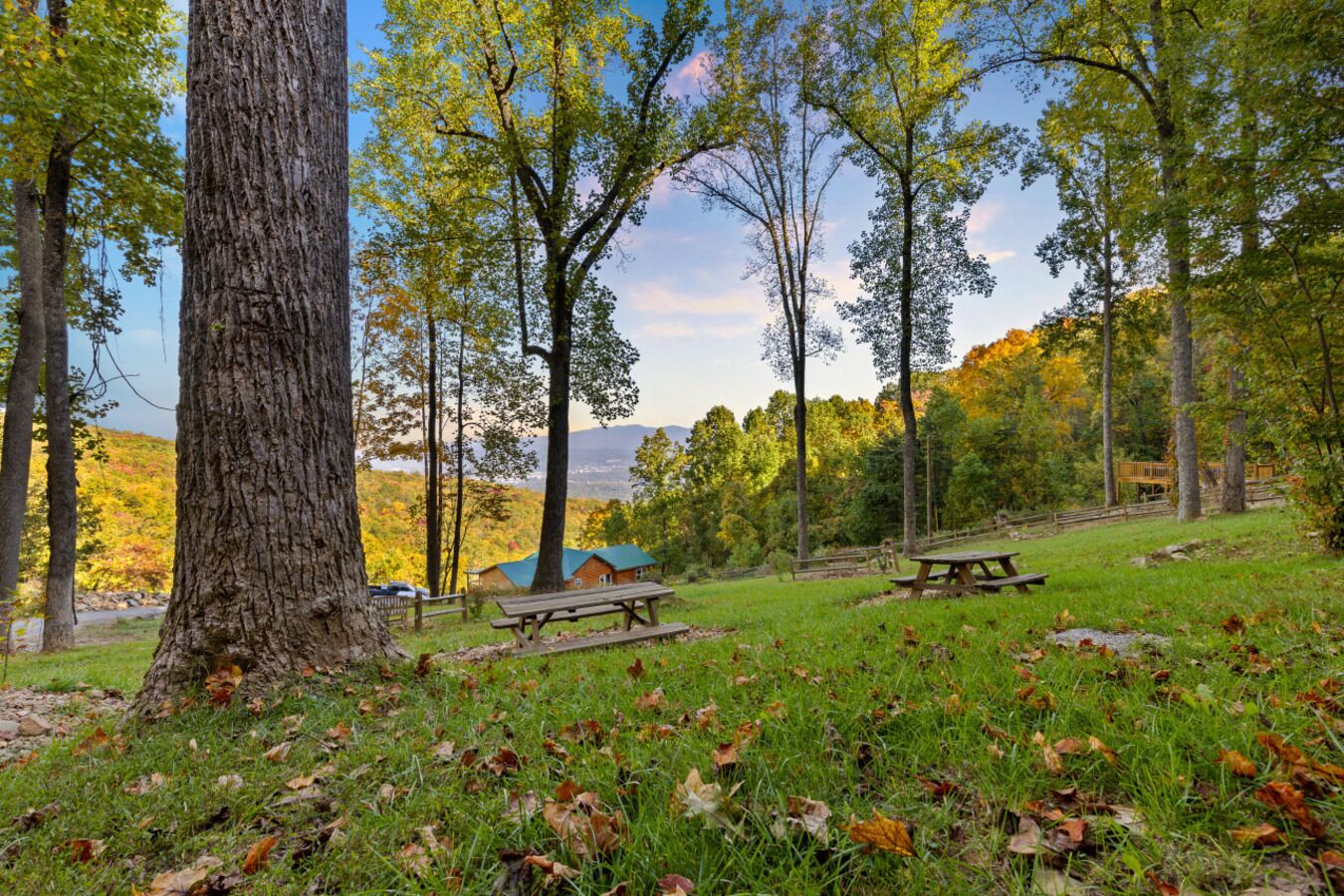 Un terrain de camping équipé de tables de pique-nique, d’un chalet et offrant une vue sur un lac et des montagnes.