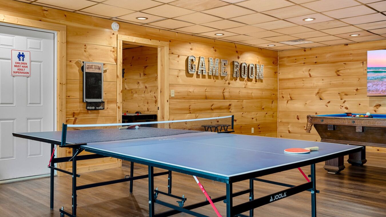 A game room with a ping pong table, pool table, and a sign indicating it is a game room.