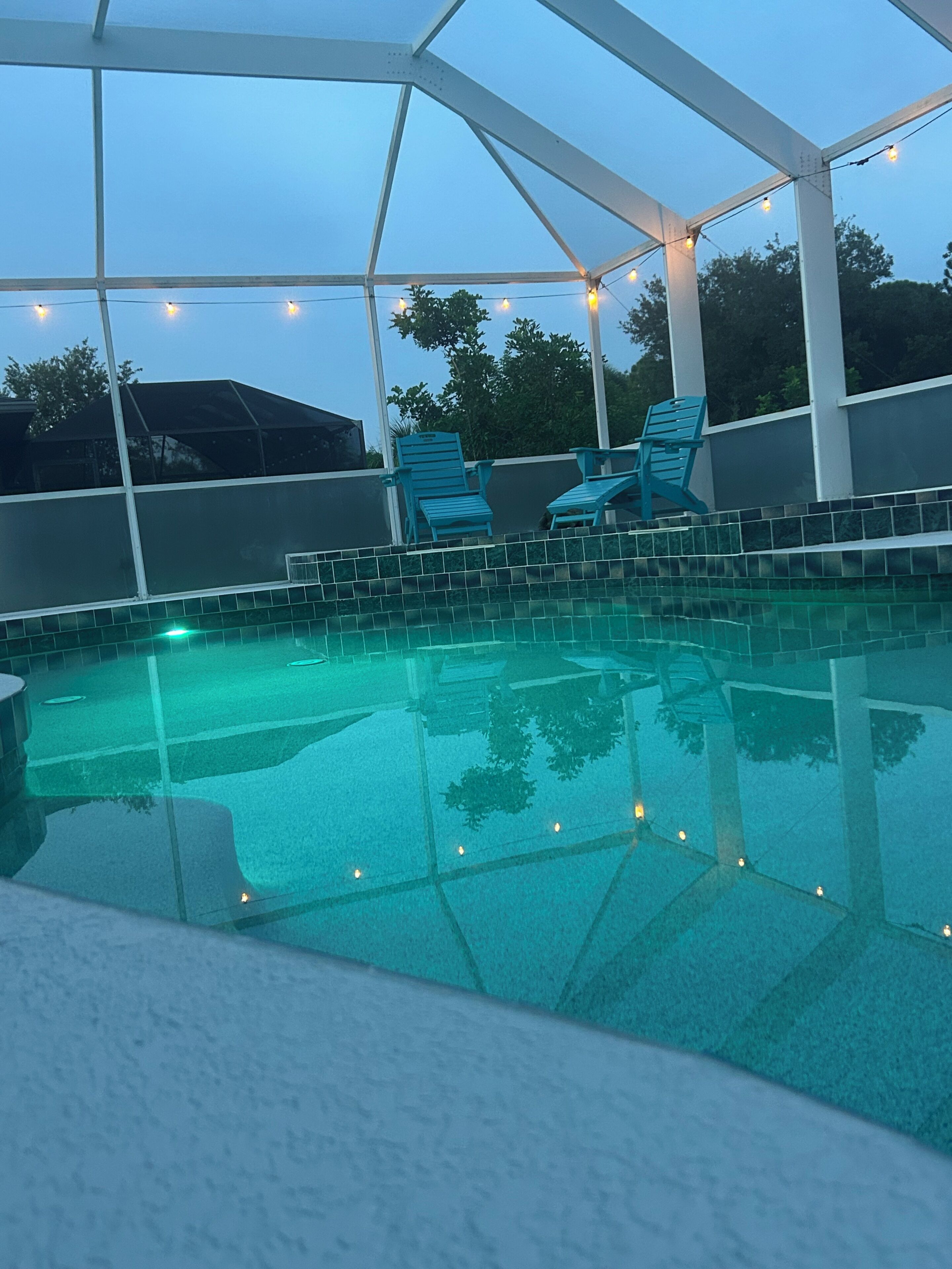 A swimming pool with a glass bottom, surrounded by a white structure with chairs.