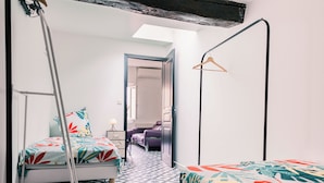 Een kamer met twee bedden, een ladder, een hanglamp en een kamer met een patroon op de vloer.