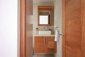 A bathroom with wooden cabinets, a white sink, and a mirror. - ResCristamar CMA304 Cabarete POP (Cabarete)