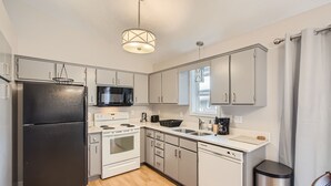Una cocina moderna con electrodomésticos de acero inoxidable, armarios blancos y suelo de madera.