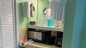 Una cocina equipada con microondas, tostadora y horno. Hay cristalería y platos en la encimera.