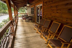 A wooden cabin with a porch, furnished with chairs and a table, overlooking a natural landscape. - Alpine Vista (Lenoir)