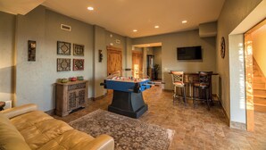 A spacious living room with a foosball table, a comfortable sofa, and a bar area with stools. - Alpine Vista (Lenoir)