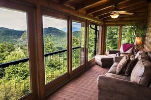 A room with large windows offering a view of a forested mountain range. - Alpine Vista (Lenoir)