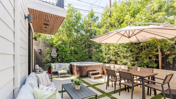 Un patio con sofá, sillas, una mesa y un jacuzzi.
