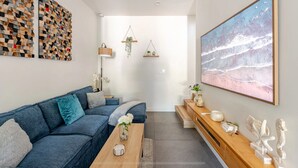 Una sala de estar moderna con un sofá azul, una mesa de centro de madera y un cuadro abstracto grande.