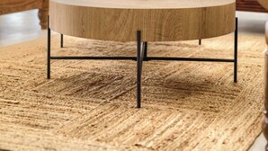 Una mesa redonda de madera con un candelabro en el centro, una alfombra tejida y una silla de madera.